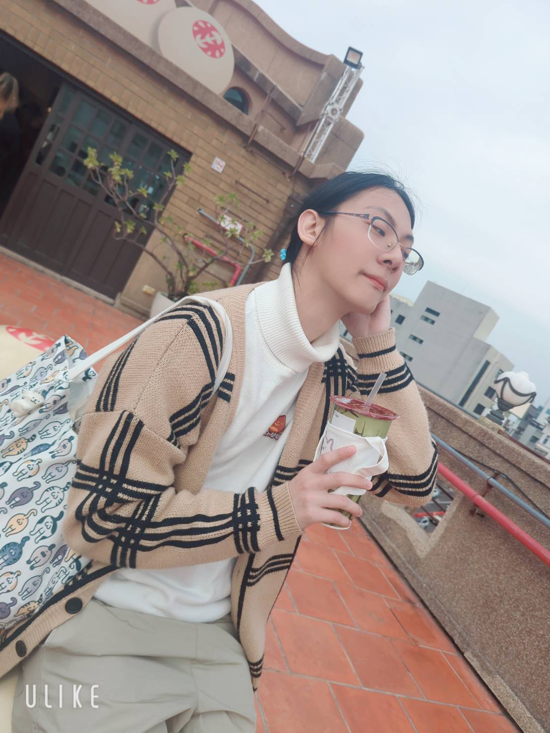 絵夢羽さ沂坐在戶外座位上拿著飲料的生活照